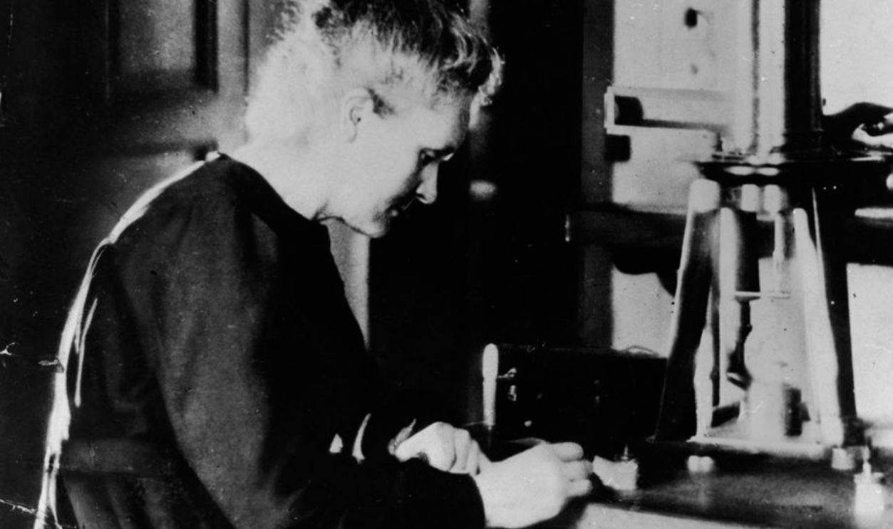 Polish Nobel Prize-winning chemist Marie Curie (1867 - 1934) working at her laboratory desk next to a large burner, c. 1920. 