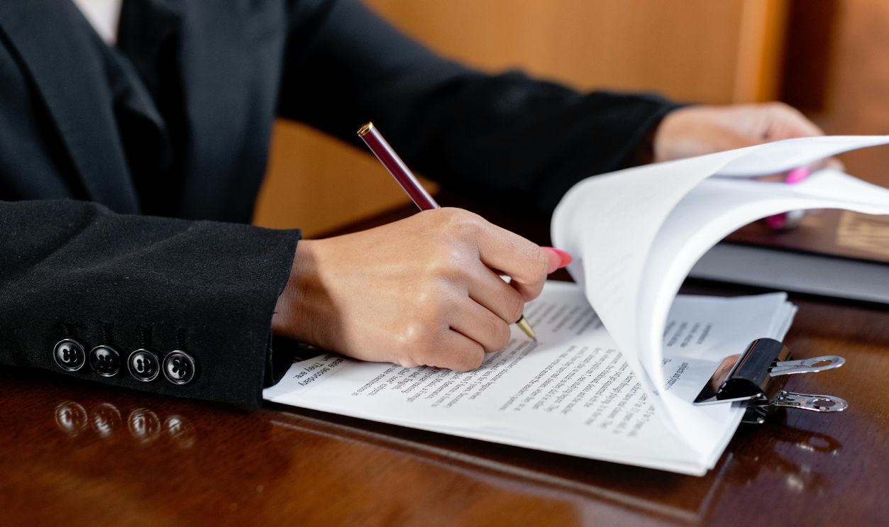 Close-up of a woman signing legal documents with a pen in an office setting