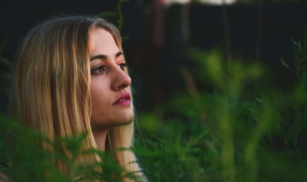 Portrait of a blonde woman surrounded by greenery at sunset