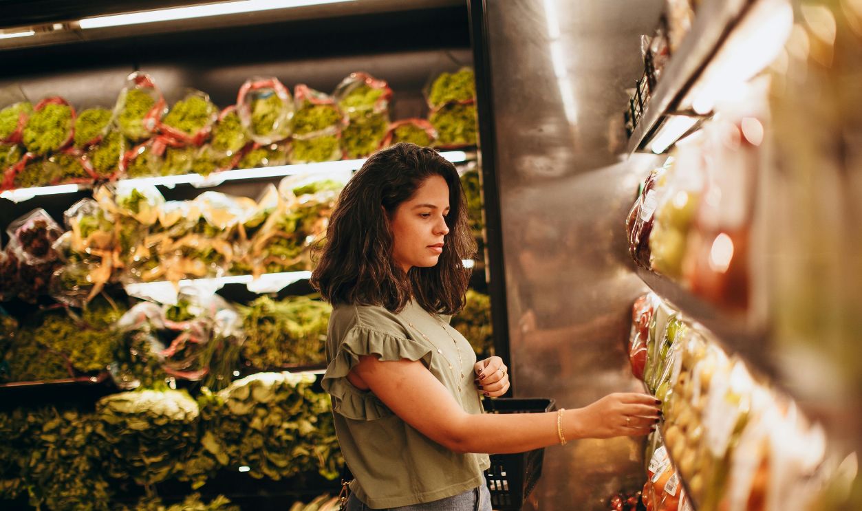 Young woman selecting fresh vegetables in a supermarket produce aisle