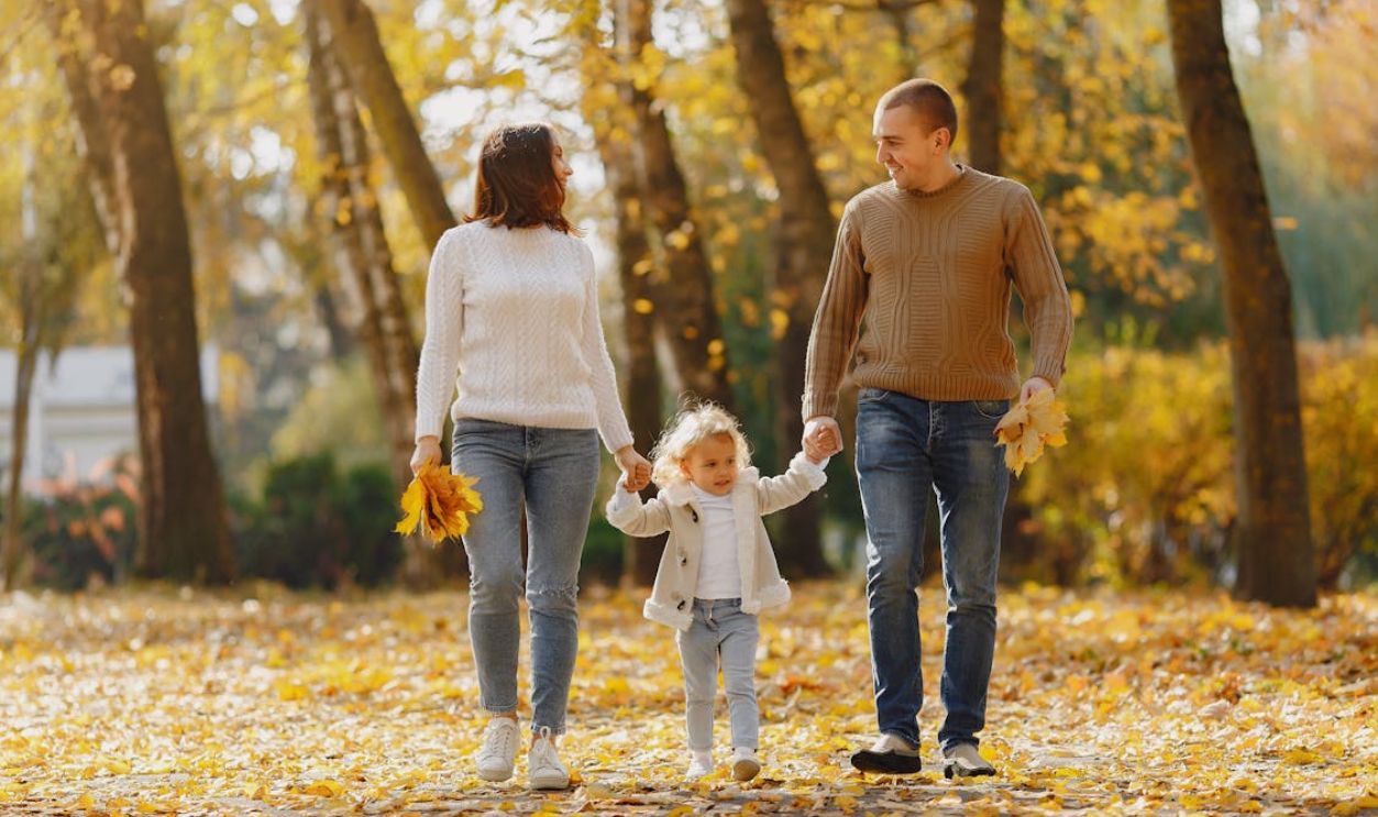 A joyful family enjoying a walk in an autumn park, surrounded by golden leaves.