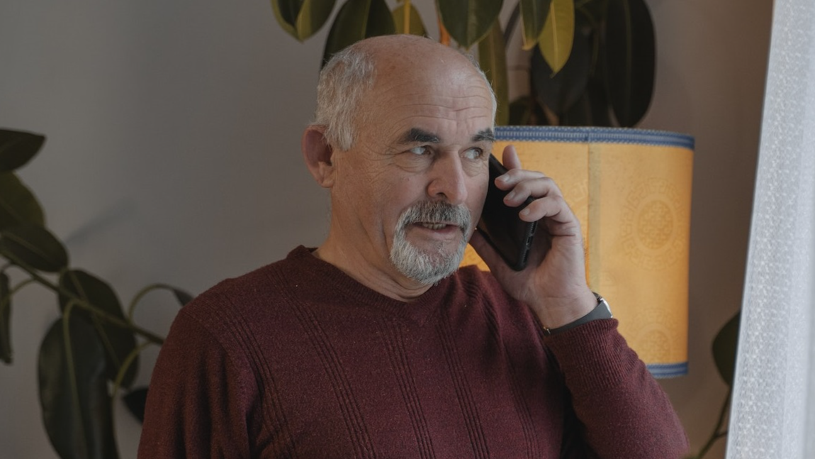 Senior man in a cozy room having a conversation on his phone, surrounded by indoor plants