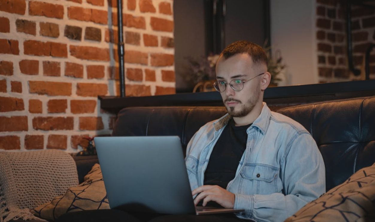 A man in casual attire working on a laptop indoors, symbolizing remote work lifestyle