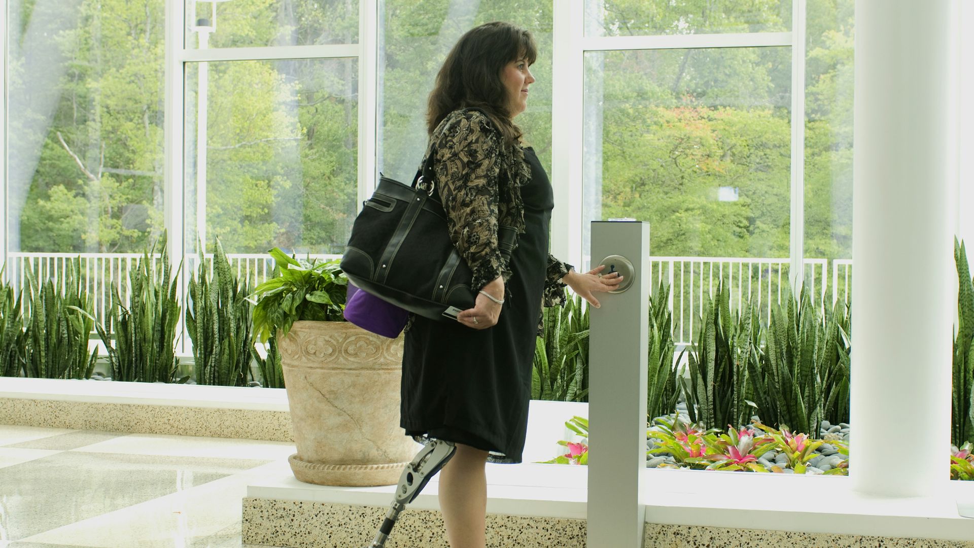 a woman with a handbag is standing near a door