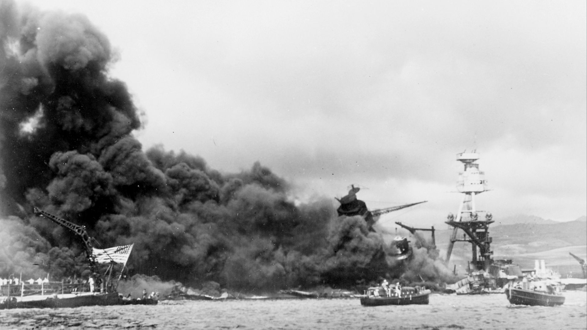 The sunken U.S. Navy battleships USS West Virginia (BB-48, left) and USS Arizona (BB-39) aflame, after the Japanese attack on Pearl Harbor on 7 December 1941.