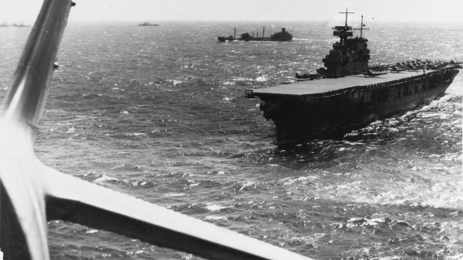 The U.S. Navy aircraft carrier USS Yorktown (CV-5) operating in the Pacific in February 1942, photographed from a Douglas TBD-1 torpedo plane that has just taken off from her deck. Other TBD and SBD aircraft are also ready to be launched. A F4F-3