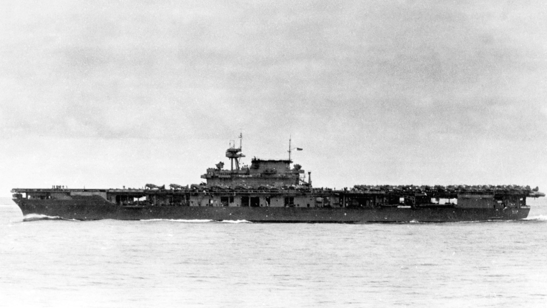 The U.S. Navy aircraft carrier USS Yorktown (CV-5) underway with her air group on the flight deck, 4 June 1942, probably about 0630-0730 hrs, following recovery of her morning search and respotting the flight deck with her strike group. Several Douglas SBD Dauntless scout bombers are on deck alongside and forward of the island, with many other planes densely parked aft. Douglas TBD-1 Devastator torpedo bombers are at the flight deck's rear.