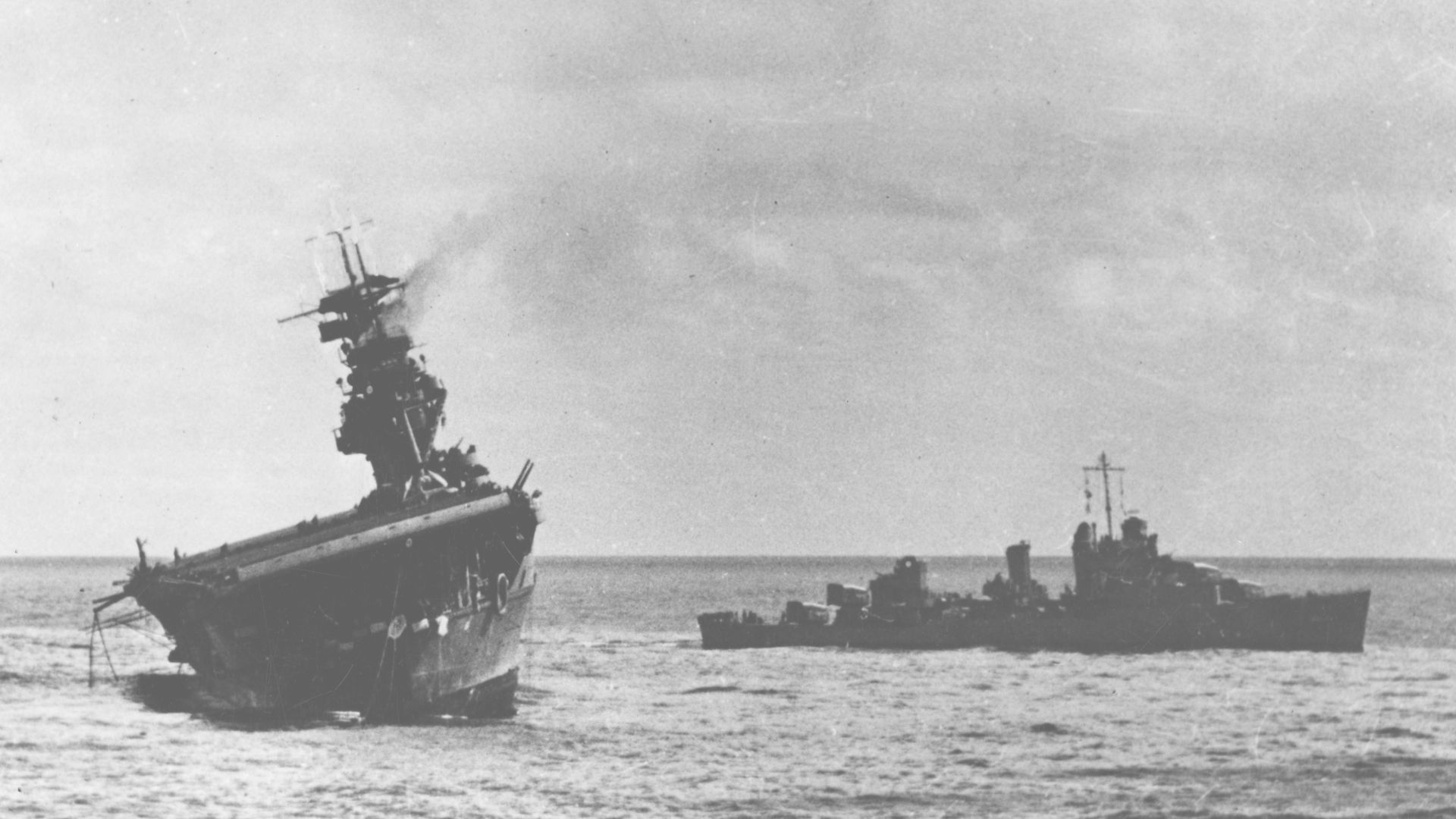 The U.S. Navy aircraft carrier USS Yorktown (CV-5) being abandoned by her crew after she was hit by two Japanese Type 91 aerial torpedoes, 4 June 1942. The destroyer USS Balch (DD-363) is standing by at right. Note the oil slick surrounding the damaged carrier, and inflatable life raft being deployed off her stern. Note that the wartime censor has erased the CXAM-radar aboard Yorktown.