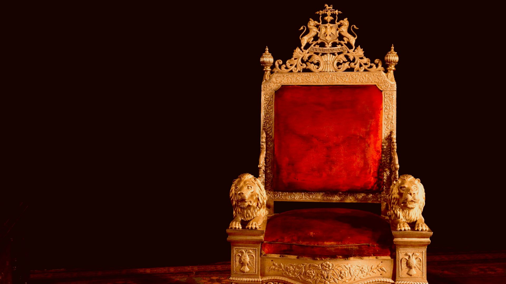 A gold and red chair sitting on top of a wooden floor