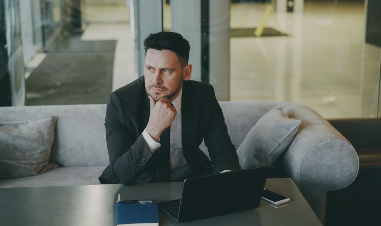 Professional businessman in suit pondering at desk in modern office lounge