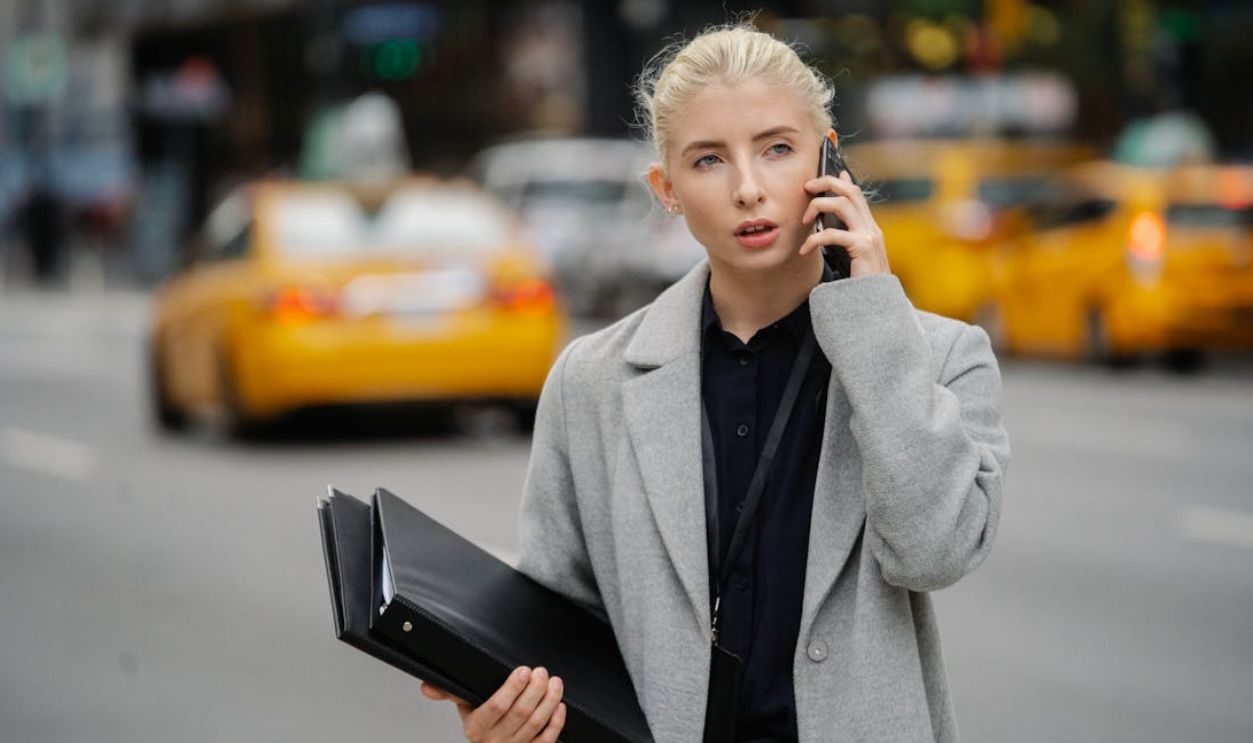 Professional woman in a city street taking a phone call, holding documents