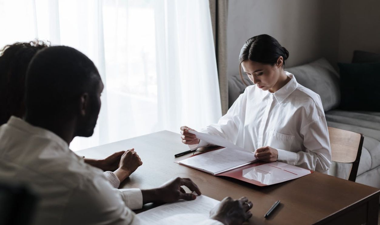 A professional woman reviews documents with a couple at home, indicating a collaborative decision-making process.