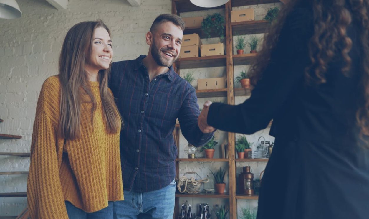 Smiling couple meets with real estate agent in a stylish indoor setting.