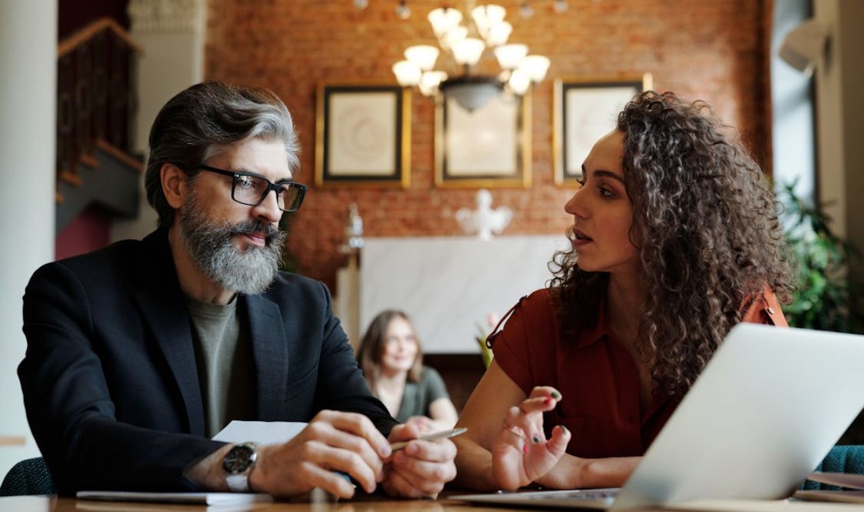 Two business professionals engaging in a strategic discussion with a laptop at a modern office.