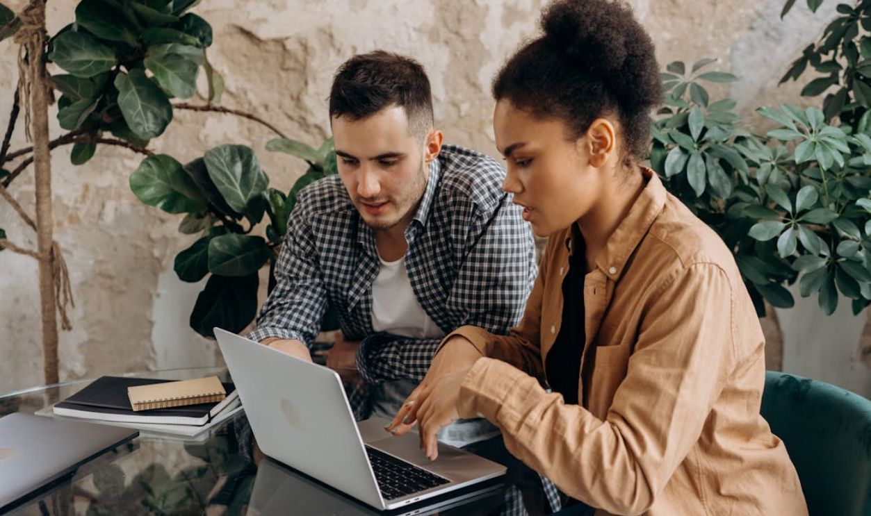 Two colleagues working together on a laptop in a modern office setting