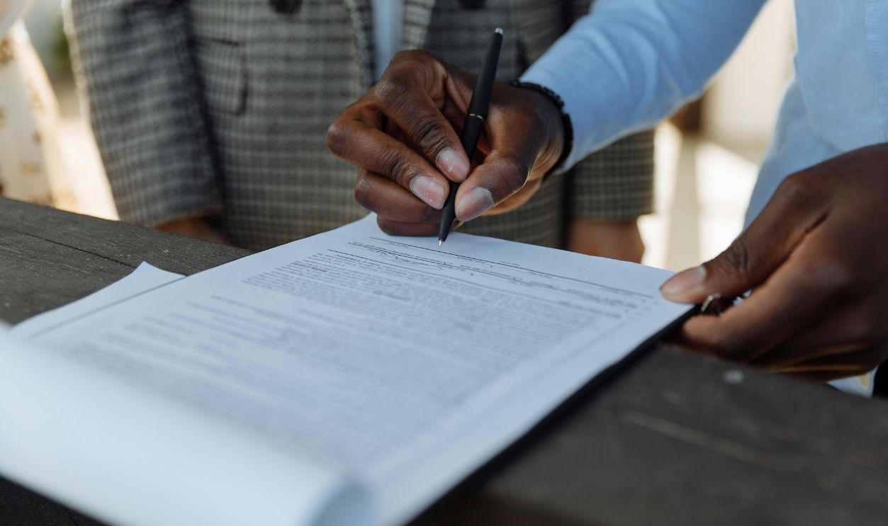 Close-up of business professionals signing a document with a pen indoors