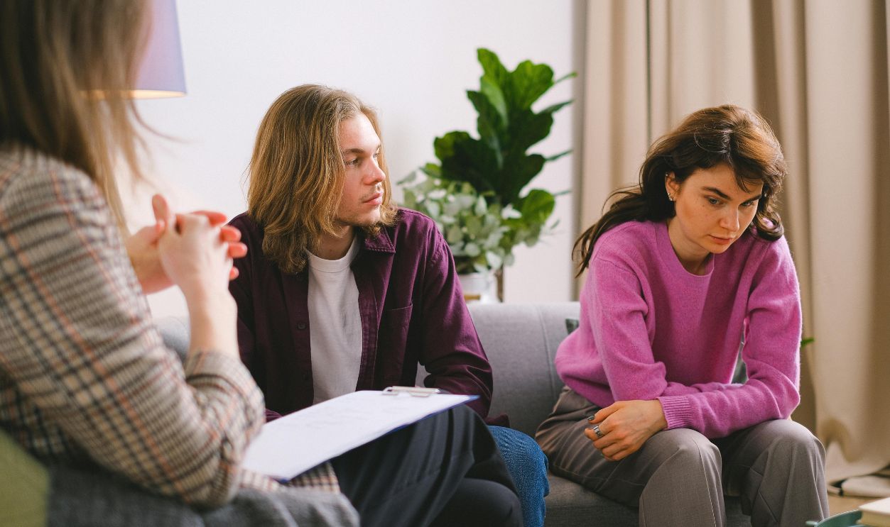 A couple engaged in a therapy session with a psychotherapist, discussing and reflecting indoors