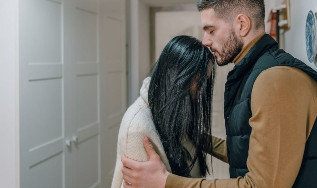 A couple shares a tender, intimate moment indoors, showcasing genuine emotion