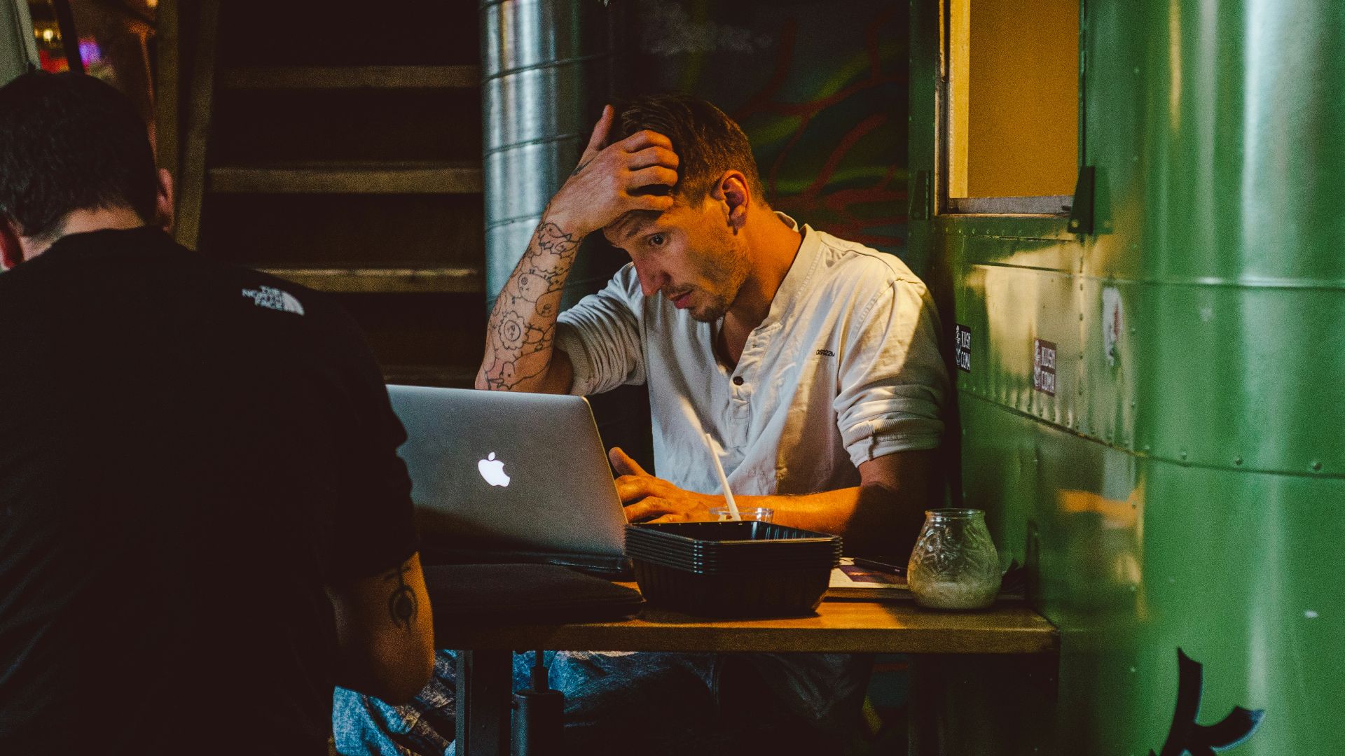 man in front of silver MacBook while scratching his head