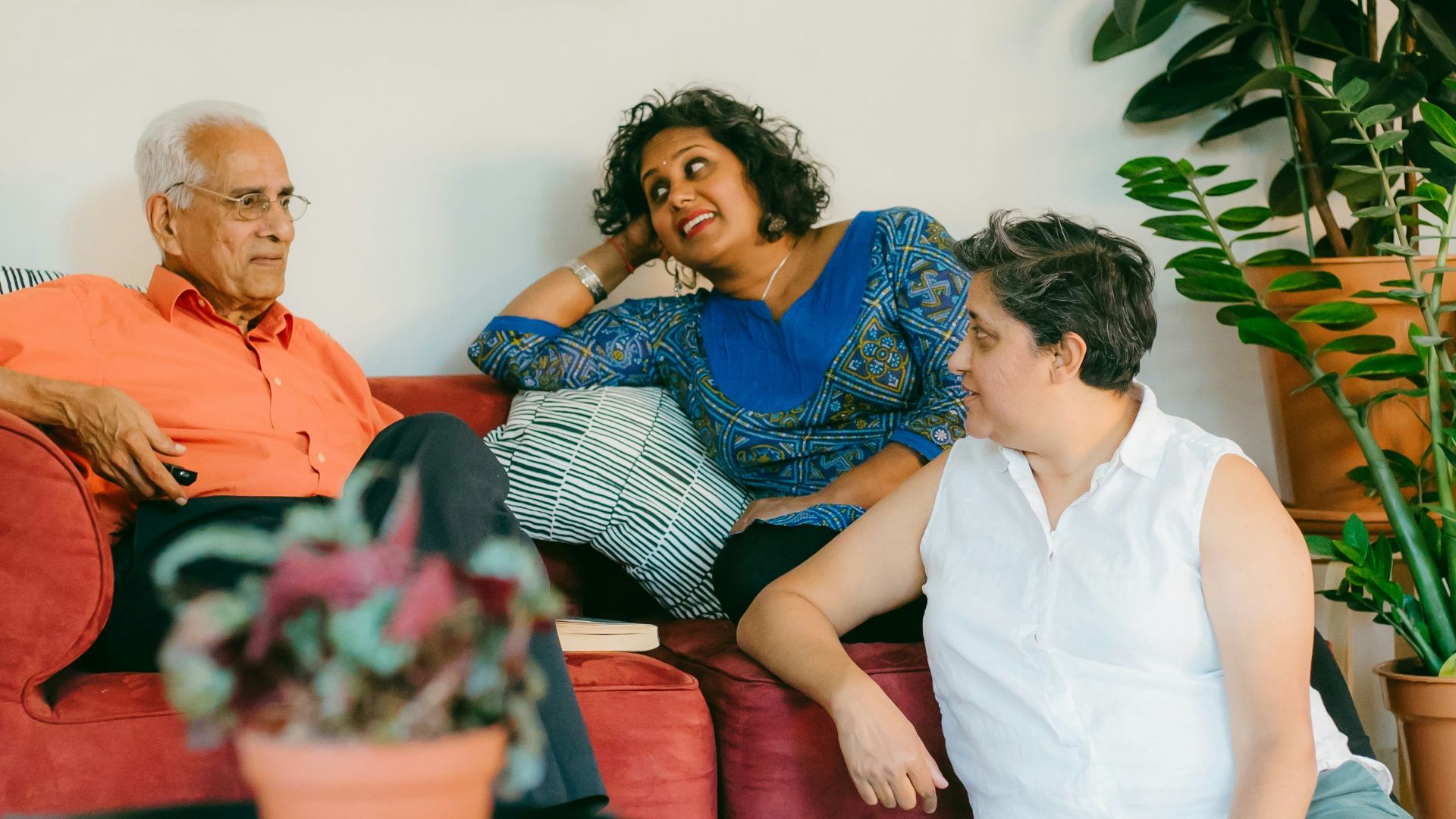 a woman sitting on top of a red couch next to a man
