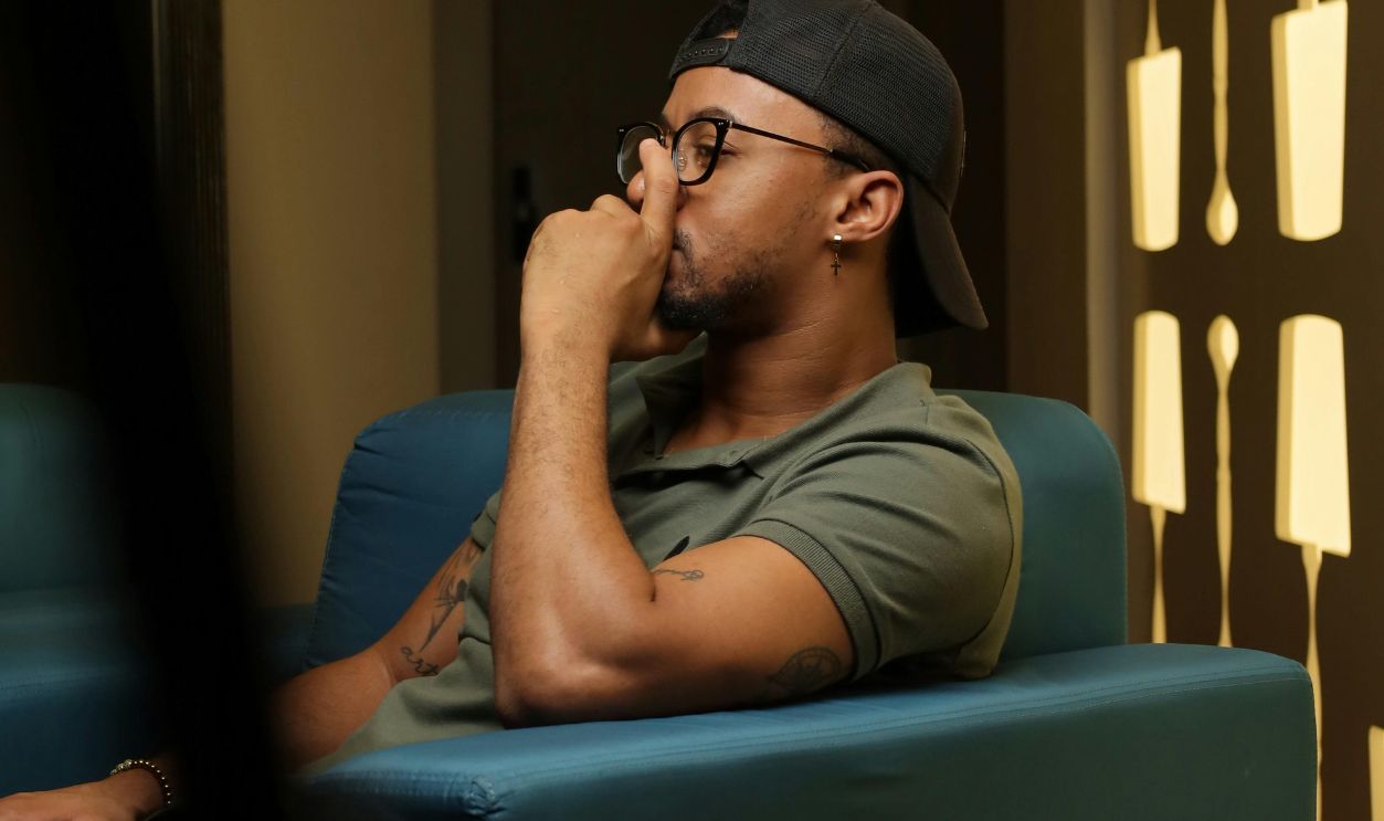 Thoughtful man sitting indoors on a modern blue chair, deep in contemplation