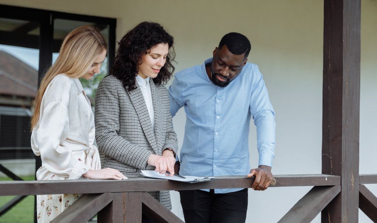 Real estate agent discussing property paperwork with a couple on a porch