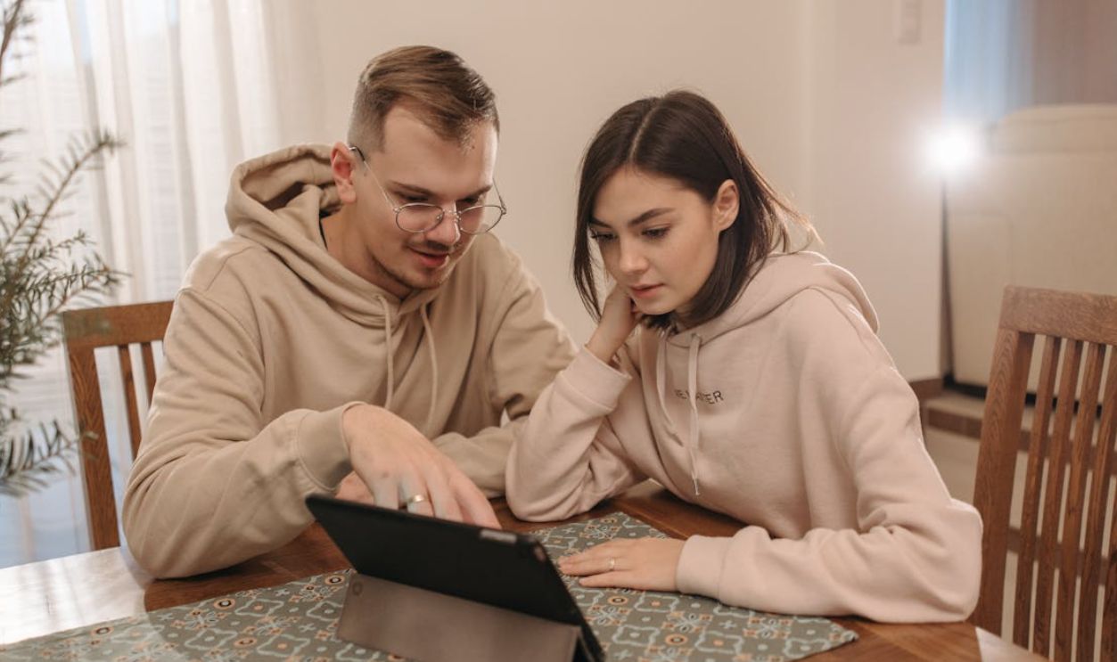 Young couple in hoodies browsing on a tablet together at home