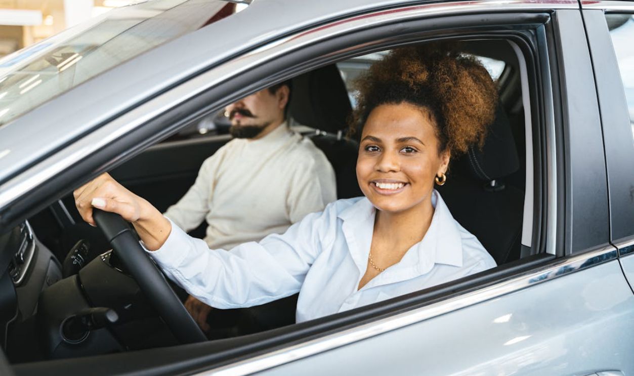 African American woman happily test driving a new car at a dealership. Capturing her joyful expression.
