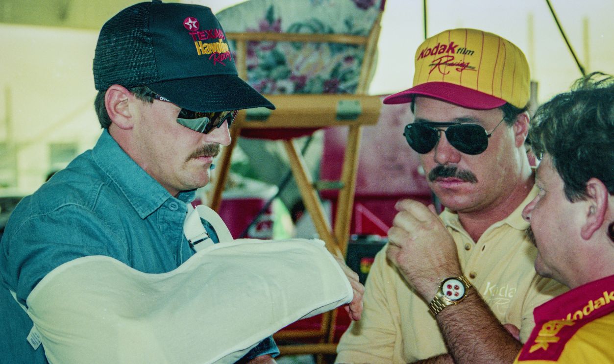Gettyimages - 974470582, NASCAR Winston 500, Talladega, 1992 TALLADEGA, AL - MAY 3, 1992: Davey Allison, L, with his arm in a sling, talks with Ernie Irvan, C, and Tony Glover before the Winston 500 NASCAR Winston Cup race on May 3, 1992 in Talladega, Alabama. 