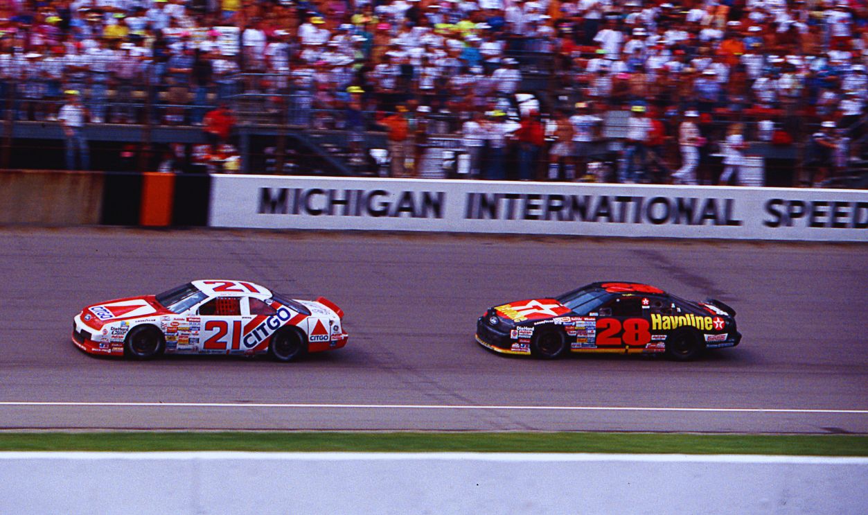 Gettyimages - 142610734, Dale Jarrett - Ist NASCAR Cup Win Michigan 1991 BROOKLYN, MI — August 18, 1991: Dale Jarrett (No. 21) in the Wood Brothers Citgo Ford leads Davey Allison (No. 28) to the checkered flag to win his first NASCAR Cup race, the Champion Spark Plug 400 at Michigan International Speedway. 