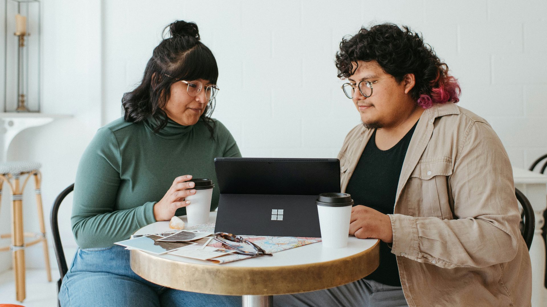 two women sitting at a table with a laptop