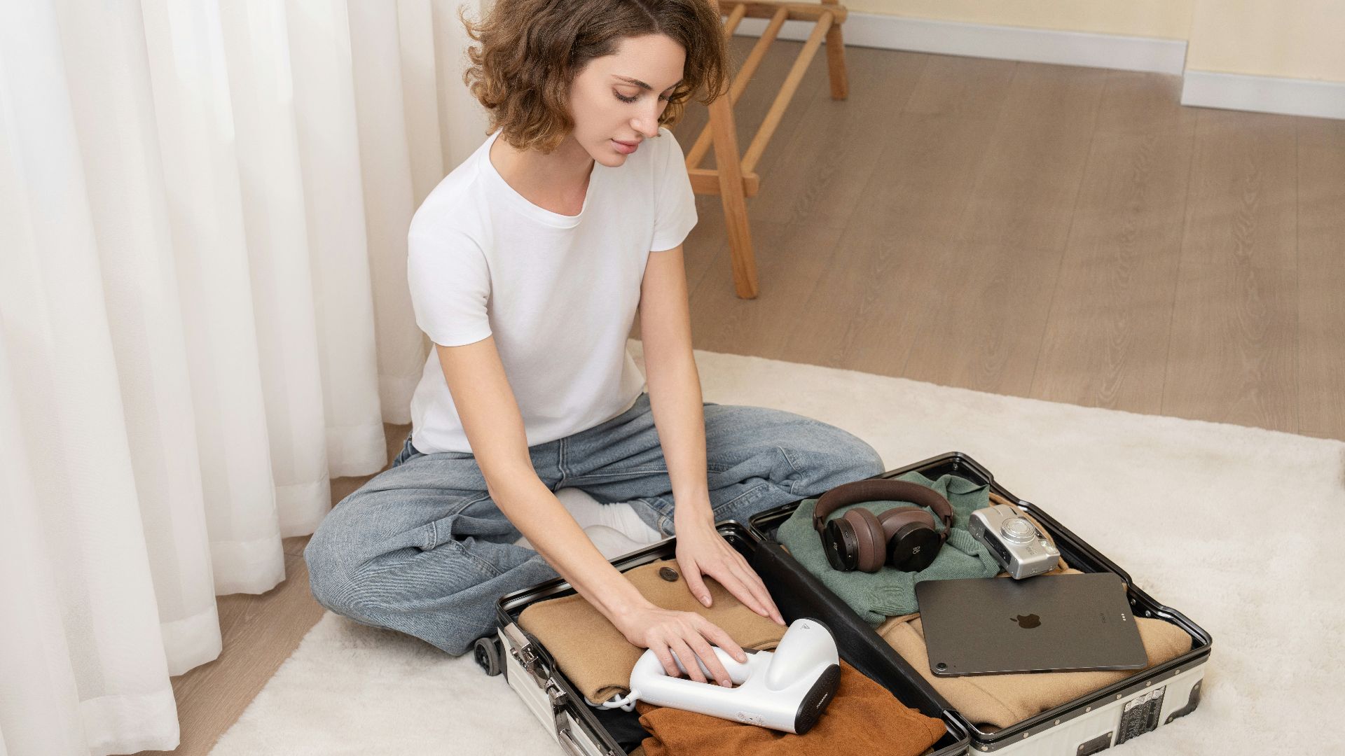 A woman sitting on the floor with a suit case