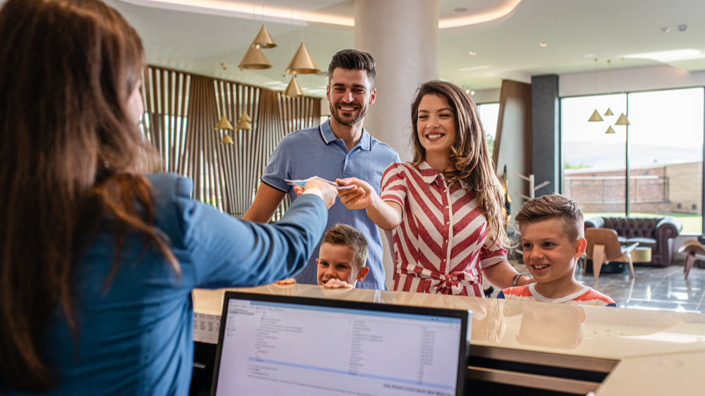 Smiling family of four in the hotel lobby check in