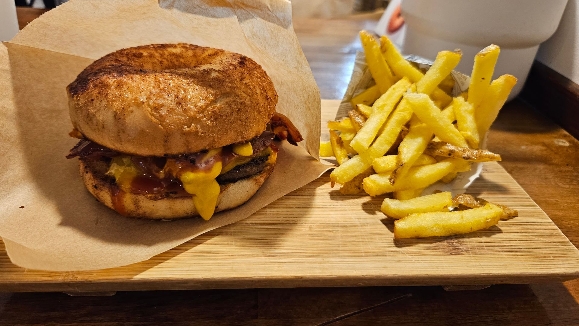 A cheeseburger inside of a cinnamon bagel with french fries on the side