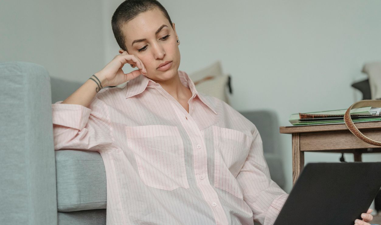 Young woman dressed casually using laptop while relaxing at home