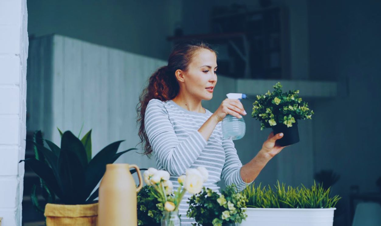 A woman waters potted plants indoors, enjoying a gardening moment at home