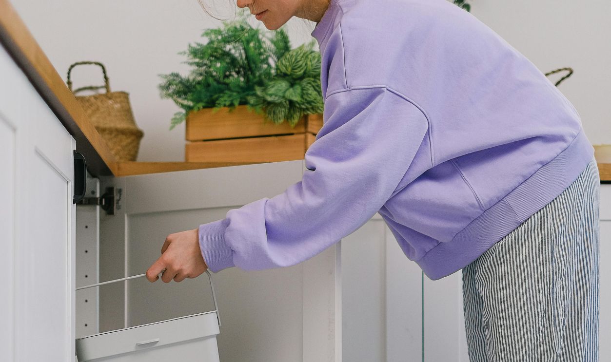 Woman sorting organic waste in a modern kitchen, highlighting eco-friendly habits and indoor organization
