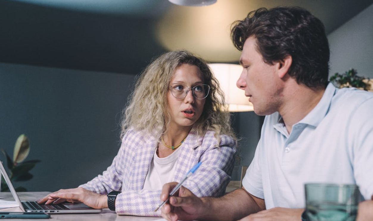 Two coworkers engaged in a focused discussion at a modern office setting.