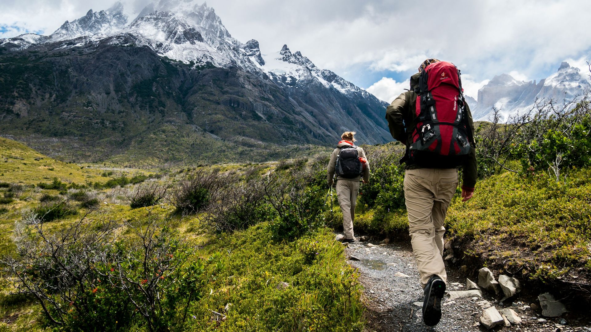two person walking towards mountain covered with snow