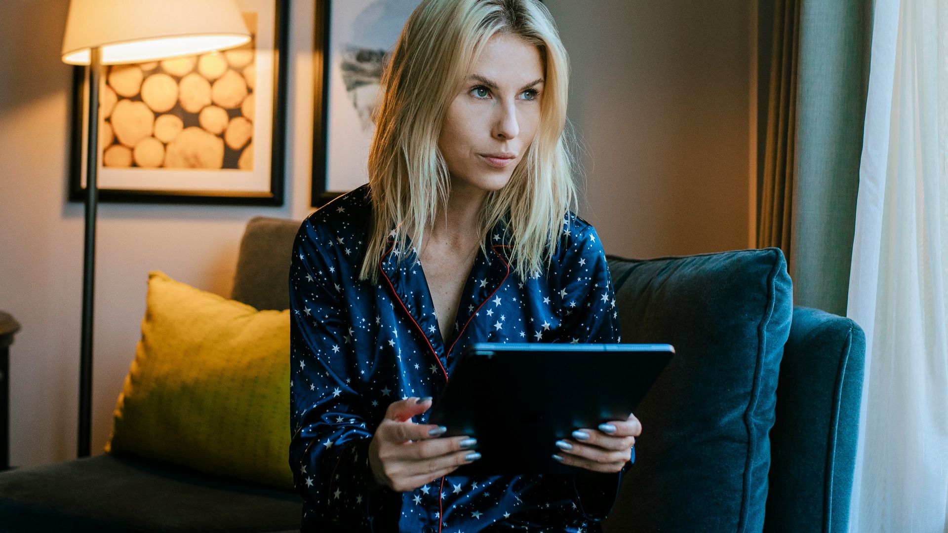 a woman sitting on a couch looking at a tablet