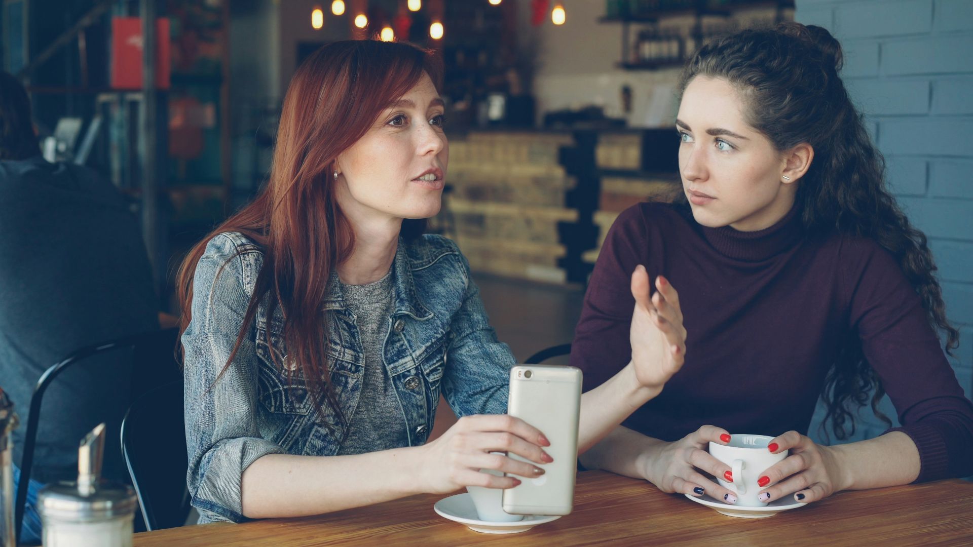 Two women converse at a cafe.