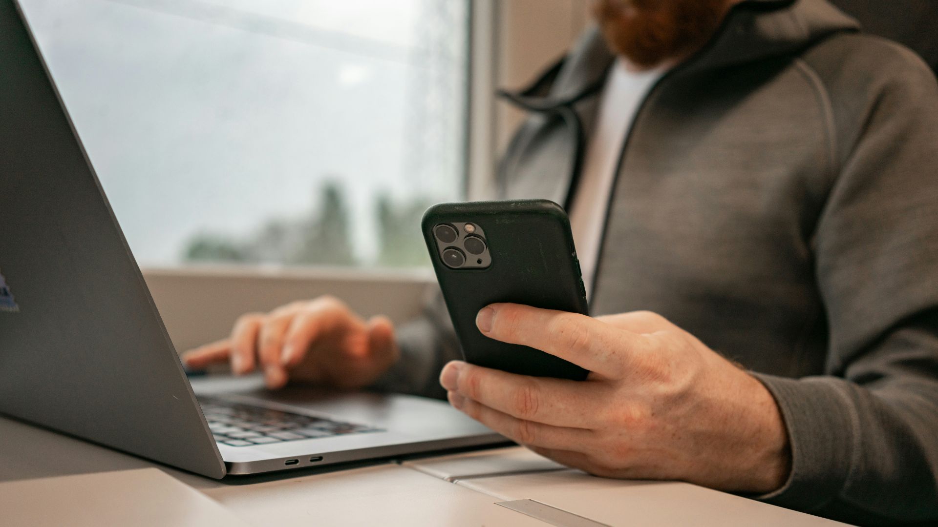a man sitting in front of a laptop computer holding a cell phone
