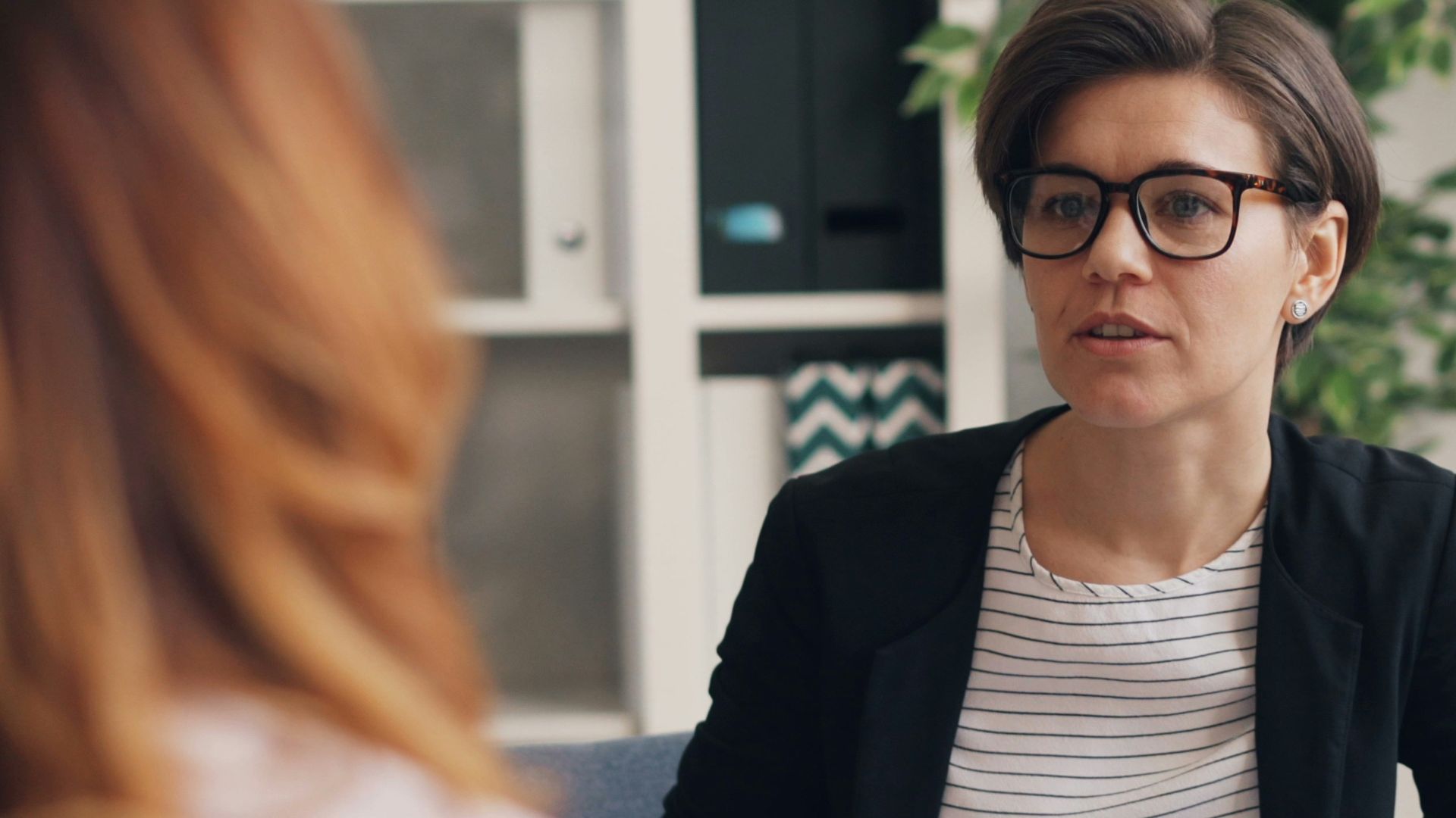 a woman sitting on a couch talking to another woman