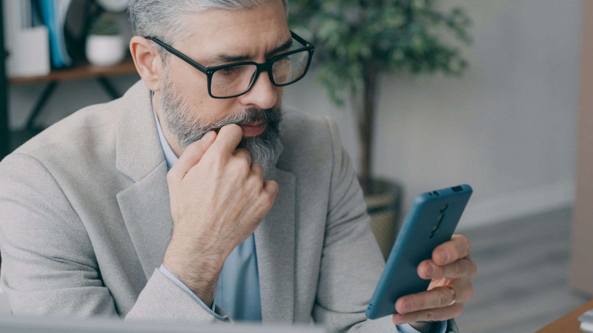 A man sitting at a desk looking at a cell phone