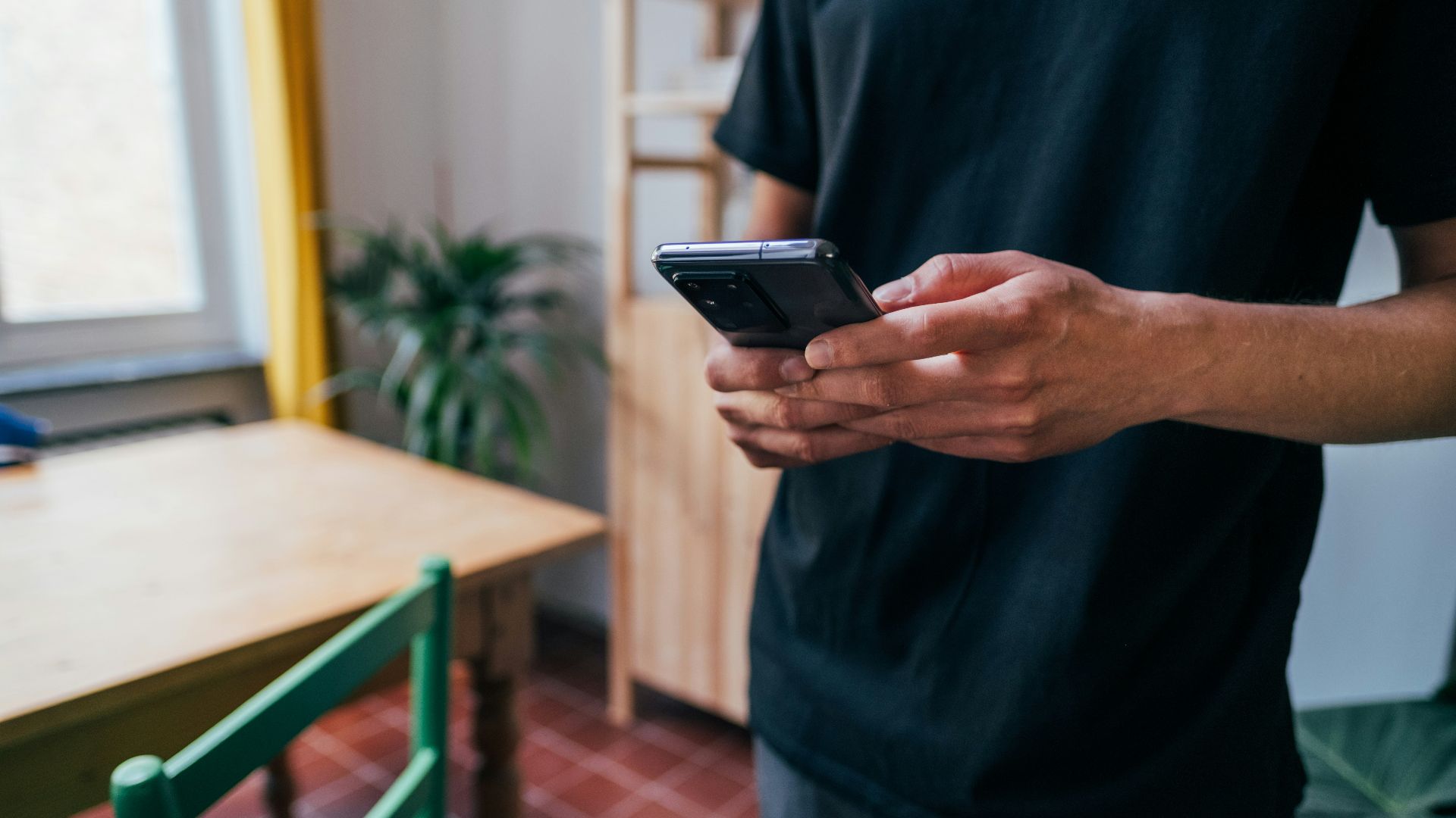 person in blue long sleeve shirt holding black smartphone