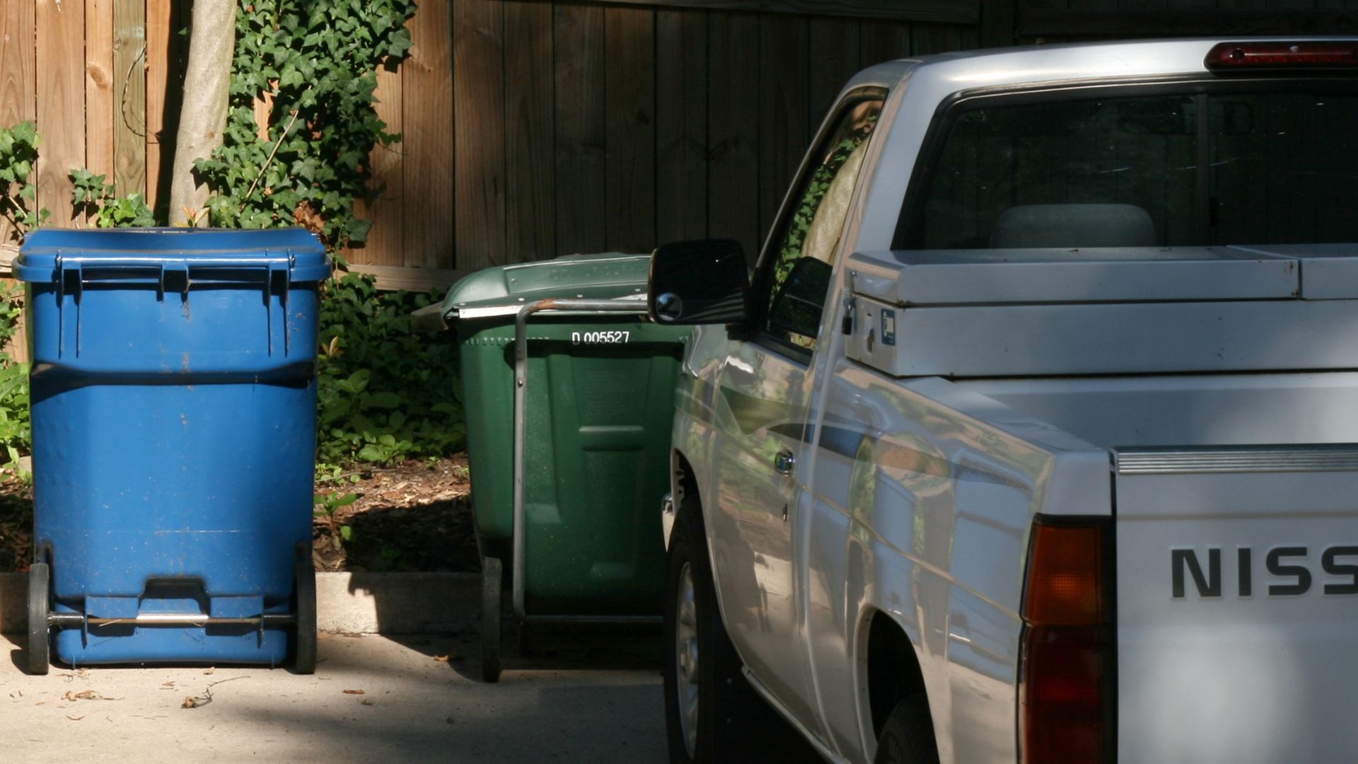 An array of four rubbish bins lined up in a driveway next to a Nissan pick-up truck on Gregson Street in Trinity Park, a neighbourhood of Durham, North Carolina.