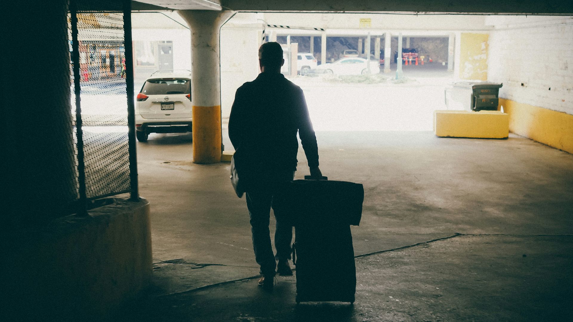 A man with a suitcase walking into a parking garage
