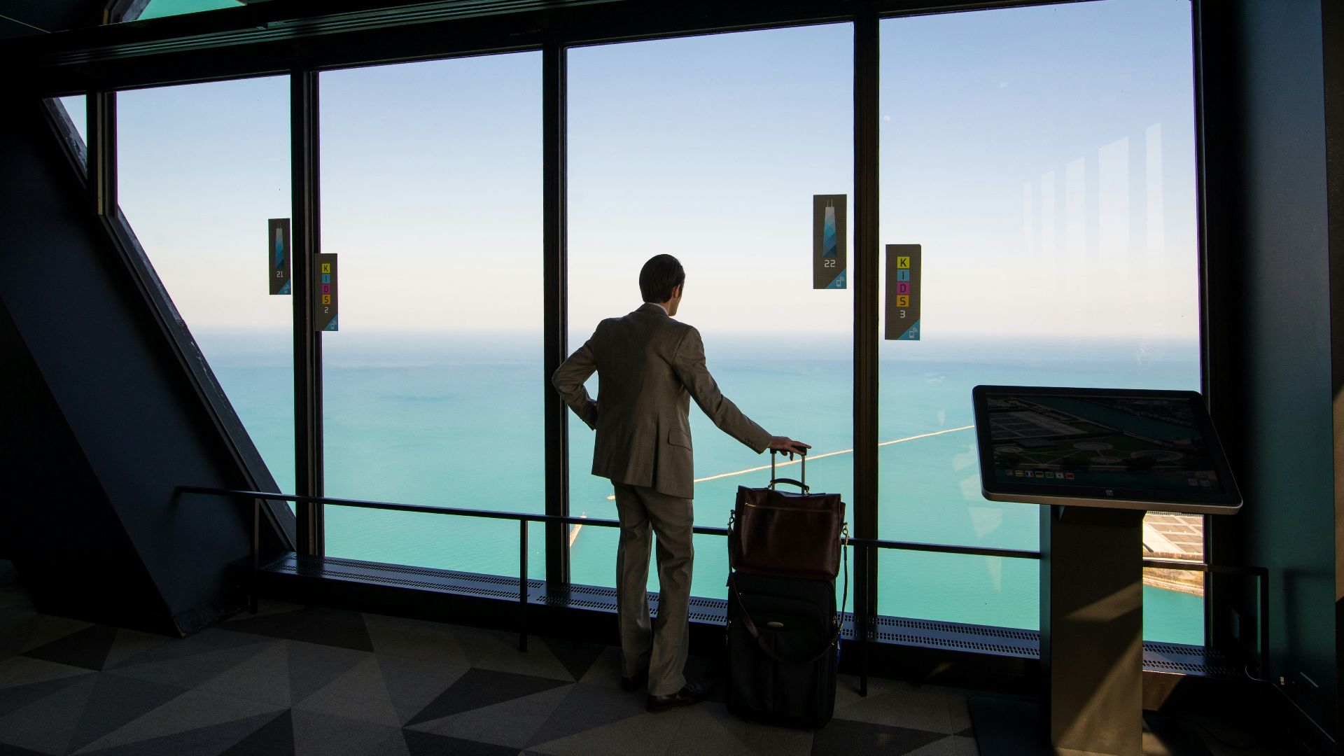 man in white shirt standing near glass window