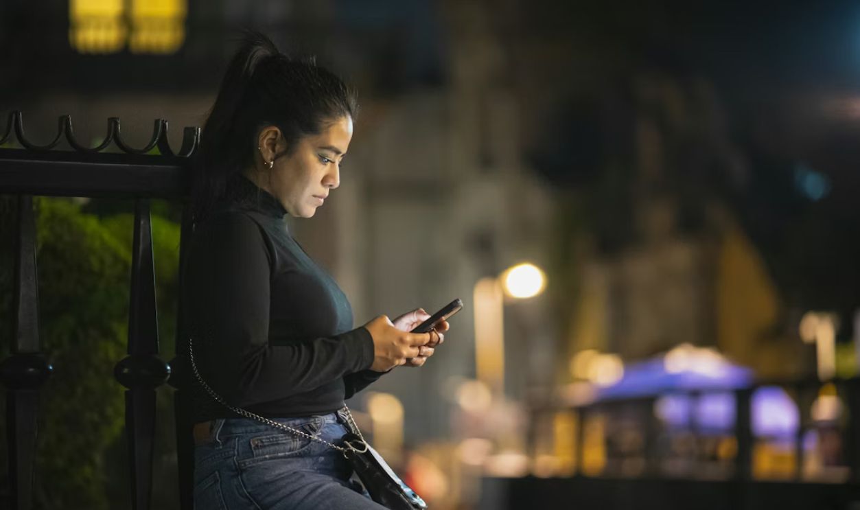 a woman sitting on a bench looking at her cell phone