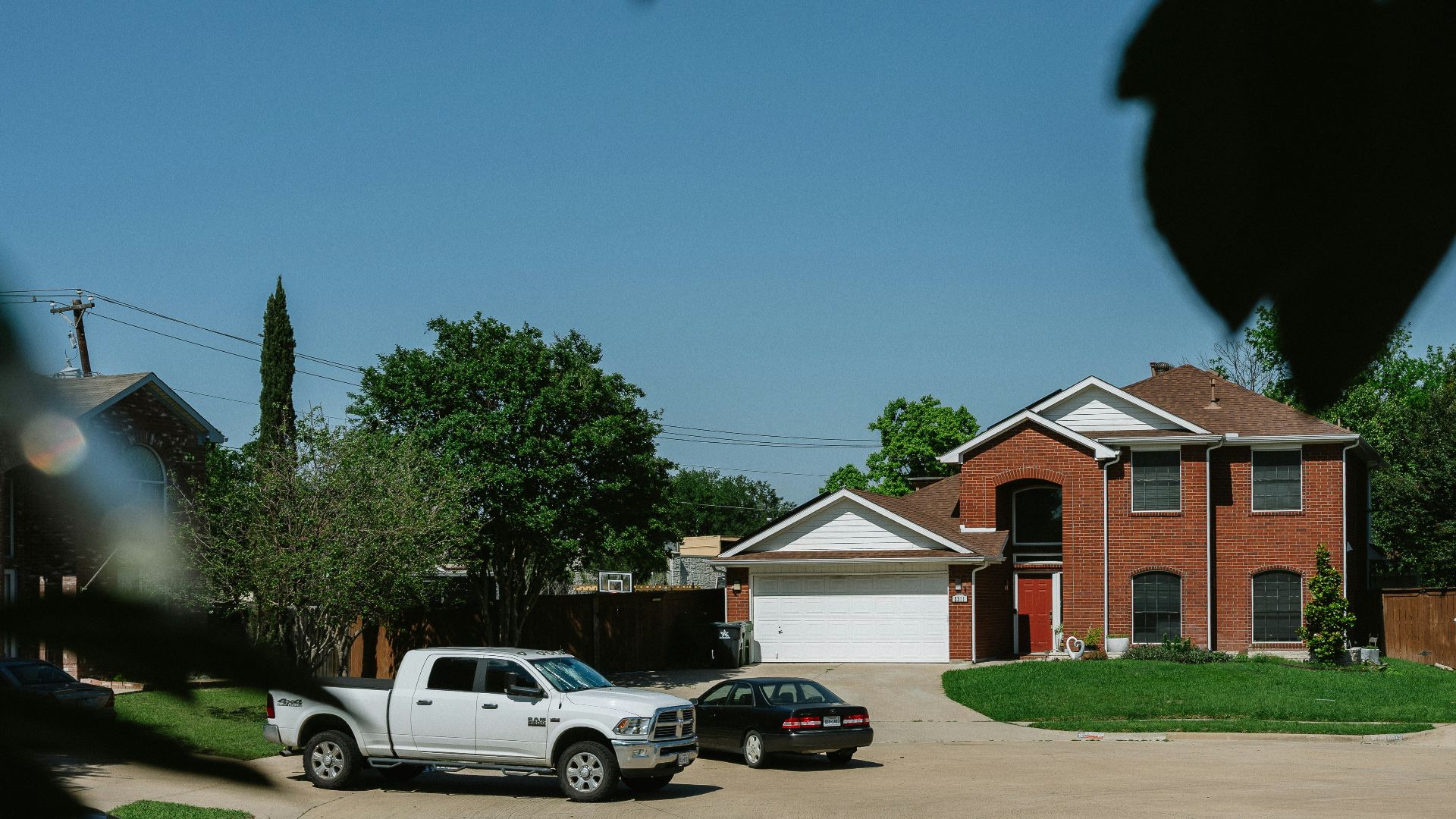 Brick house with cars in the driveway.